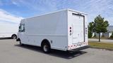 A 2011 Ford Econoline cargo van with a white exterior and no rear branding parked in an empty lot