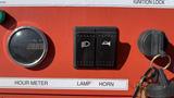 Control panel featuring hour meter, switches for lamp and horn, and ignition lock with a key attached