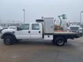 A white 2009 Ford F-450 SD truck with a flatbed and storage box on the back parked on a lot