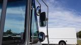 A close-up view of the front driver's side of a 2011 Ford Econoline showing the side mirrors and window