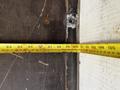 A yellow measuring tape stretched across a surface marking measurements in inches and feet