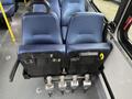 A pair of blue upholstered bus seats mounted on a black base with three metal levers underneath for adjustments