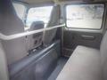 Interior view of a 2003 Toyota Toyoace showcasing the rear seating area with seatbelts and a protective bar between the front and rear seats