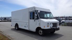 A white 2011 Ford Econoline cargo van with a boxy design and large front windshield parked on a concrete surface