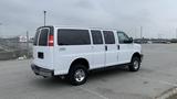 A white 2017 Chevrolet Express Quigley 4x4 van parked with side doors open and visible branding on the side