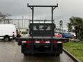 A 2006 Hino 155 flatbed truck viewed from the rear showcasing its black bed and taillights