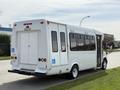 A 2010 Ford Econoline bus with a white exterior and multiple windows on one side designed for accessibility features
