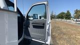 A white 2011 Ford F-450 SD with an open driver's side door showcasing the interior details and controls