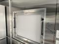 A stainless steel serving window with a clean, white panel designed for a food truck setup