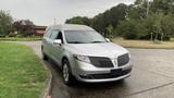 A silver 2013 Lincoln MKT hearse parked with a streamlined design featuring distinctive grille and tinted windows