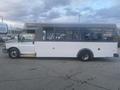 A 2017 Chevrolet Express shuttle bus with a white exterior and large windows parked on a paved surface