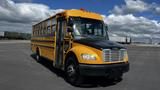 A yellow and black 2014 Freightliner Thomas bus with large windows and a front grille visible