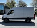 A 2022 Mercedes-Benz Sprinter van shown from the side featuring a white exterior and a sleek design with a high roof and large cargo space