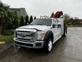 A 2014 Ford F-550 pickup truck with a shiny silver exterior and a utility bed equipped with tools and equipment