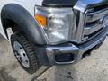 A 2013 Ford F-450 SD with a shiny chrome grille and large circular headlights is shown with a rugged tire and black wheel well trim