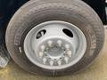 Close-up of a silver wheel rim from a 2014 RAM 5500 with a black tire featuring a tread pattern and multiple lug nut fittings