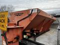 A 2009 Ford F-550 truck with an orange Swenson spreader mounted on the back designed for distributing materials like salt or sand