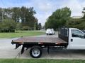 A 2012 Ford F-550 with a flatbed and a black mesh gate on the back parked on a driveway