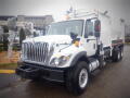 A white 2008 International 7400 truck features a large front grille with vertical slats and a boxy shape with a cargo area mounted on the rear