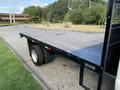 A 2013 Ford F-450 SD with a flatbed bed visible from the rear angle showcasing the wooden surface and the dual rear wheels