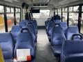 Interior of a 2018 Chevrolet Express showing rows of blue upholstered seats with a fire extinguisher and safety information on the floor