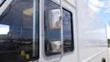 A 2011 Ford Econoline van with a silver side mirror and a large window reflecting the surroundings