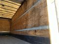 Interior view of a 2013 International 4300 truck with wooden walls and metal track for securing cargo