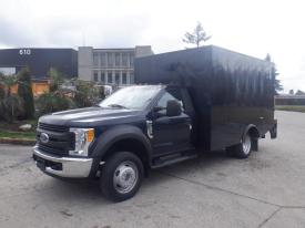 A 2017 Ford F-550 with a black box truck body parked on a paved surface