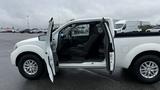 A white 2016 Nissan Frontier pickup truck with its driver side door open showcasing the front seat and interior details