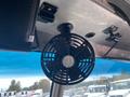 A black circular fan mounted on the ceiling of a food truck with a metallic interior and visible control switches