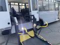 A 2017 Chevrolet Express with a wheelchair lift in the foreground, featuring yellow handles and a wide platform for accessibility