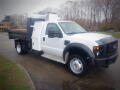 A 2008 Ford F-550 truck with a white cab and flatbed, featuring rear toolboxes and orange clearance lights on the roof