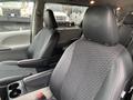 A 2013 Toyota Sienna interior featuring two front seats with black cloth and leather accents and a central console with cup holders