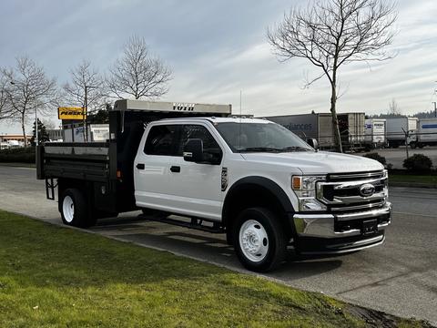 A 2021 Ford F-550 truck with a flatbed design in white color parked on the street