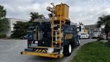 A blue 2009 International 4300 utility truck with a yellow aerial lift and various equipment mounted on its rear side