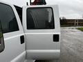 A white 2014 Ford F-550 with an open door showing the interior space and a window on the side