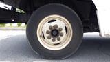 A close-up view of a 2011 Ford Econoline wheel featuring a white rim with visible lug nuts and a black tire