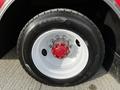 Close-up of a truck wheel featuring a white rim with a red hub and a black tire showing deep treads