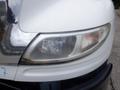 Close-up of the headlight of a 2015 International 4400 showing a damaged lens and chrome trim