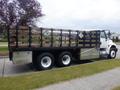 A 2015 International 4400 truck with a flatbed and wooden siding featuring several warning labels on the sides