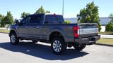 A 2017 Ford F-350 Super Duty truck in a gray color with FX4 badge and large chrome wheels viewed from the rear angle