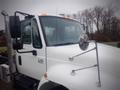 A white 2006 International 4300 truck featuring side mirrors and a chrome exhaust stack with the model number displayed on the door