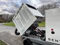 A 2007 Tennant Sentinel with its waste hopper tilted up for emptying featuring a large white container and red hydraulic mechanisms