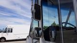 A 2011 Ford Econoline van with a silver exterior and large front windows is shown from an angled perspective focusing on the side mirrors and driver's area