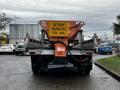 A 2009 Ford F-550 truck with a mounted orange sign displaying "STAY BACK 15 m" on the rear and a flatbed construction body