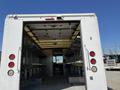 A 2011 Ford Econoline with an open rear cargo area showing metal shelving units along the sides and a clear view towards the front of the vehicle