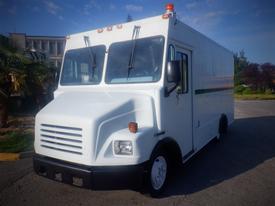 A white 2006 Freightliner MT45 Chassis with a flat front design and multiple windows on the cab area