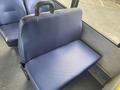 A blue upholstered bus seat with a black plastic handle on the back