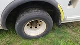 Close-up of a tire on a 2006 Ford Econoline showing some wear with a white rim and visible dirt on the tire surface