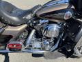 A 2004 Harley-Davidson Flhtcui motorcycle with chrome accents and a black and gold color scheme showing a close-up of the engine and seat